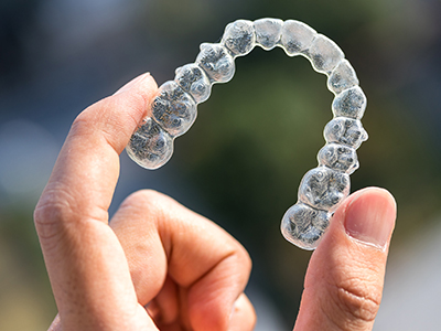 Hand holding a clear aligner tray at Stone Oak Orthodontics, Stone Oak Office and Dominion Office, San Antonio, TX