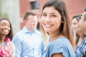 A confident teen girl with a beautiful, straight smile, representing the desired outcome of orthodontic treatment like braces or Invisalign.