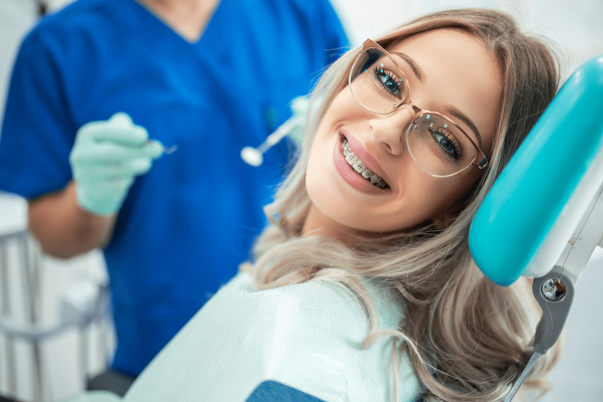 Woman wearing braces smiling in a dental chair during an orthodontic examination.